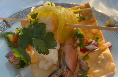 Skewered shrimp on a golden cracker with diced red onion