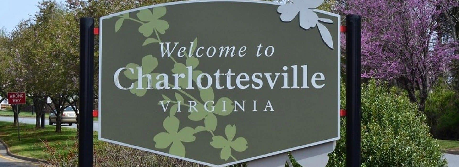 A large green sign on black posts welcoming visitors to a city