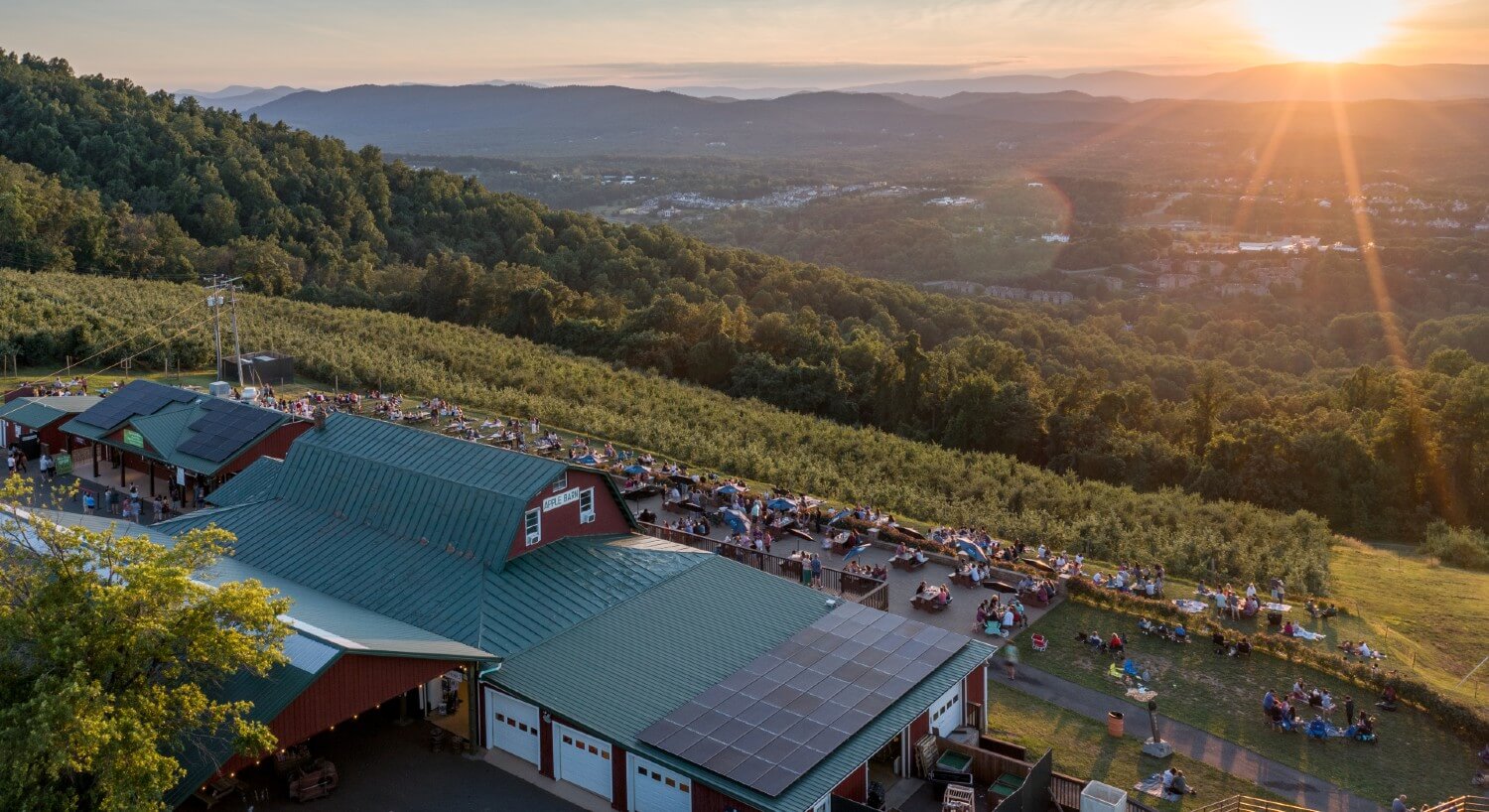 Large barn and orchard with patio overlooking an expansive valley bathed in sunlight