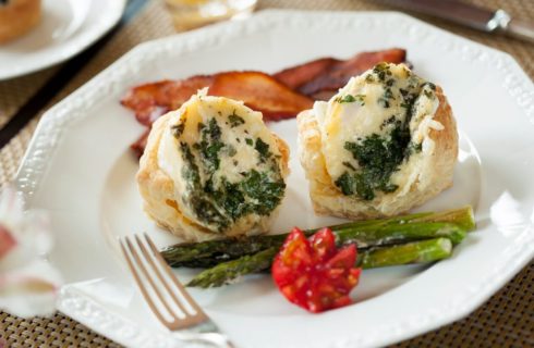 White plate with two egg biscuits, bacon and asparagus