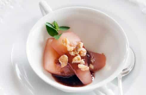 White teacup with poached pears, walnuts and sprig of mint
