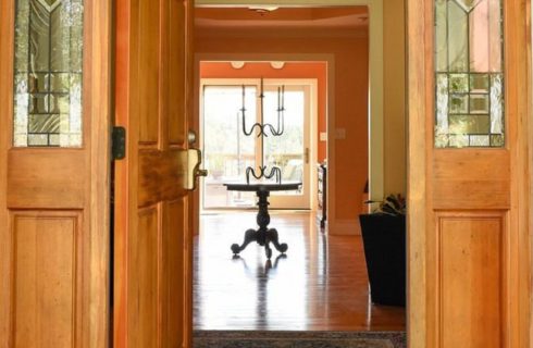 Open doorway into a large home with wood floors, and round pedestal entry table