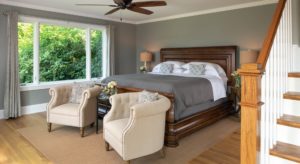 Large guestroom with king sleigh bed, large picture window and two beige club chairs