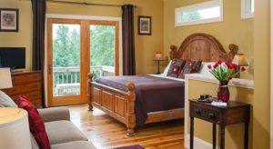 Bright bedroom with bed, loveseat, dresser with TV and sliding doors onto a patio