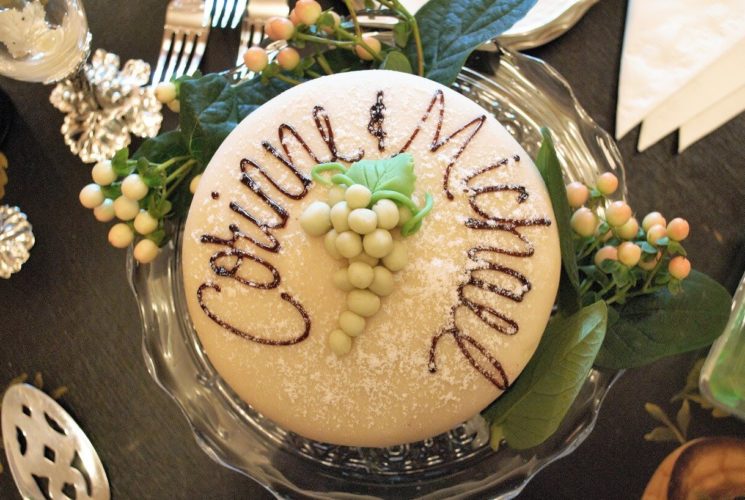 Cake with beige fondant, chocolate writing and grape cluster decoration