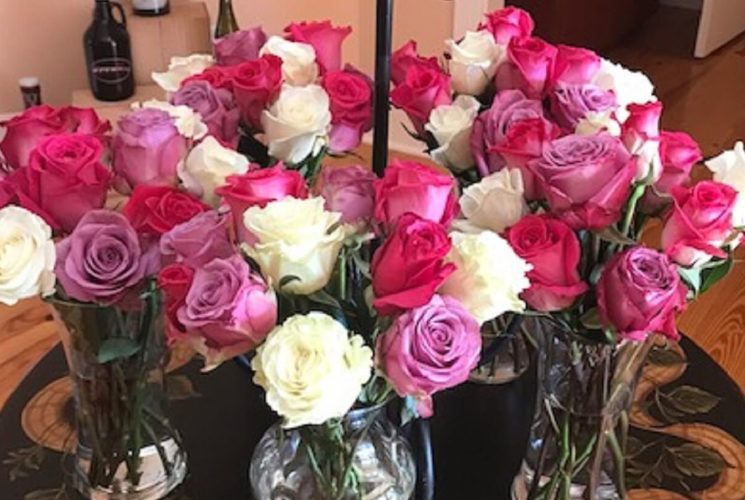 Five bouquets of white, pink and purple roses in glass vases