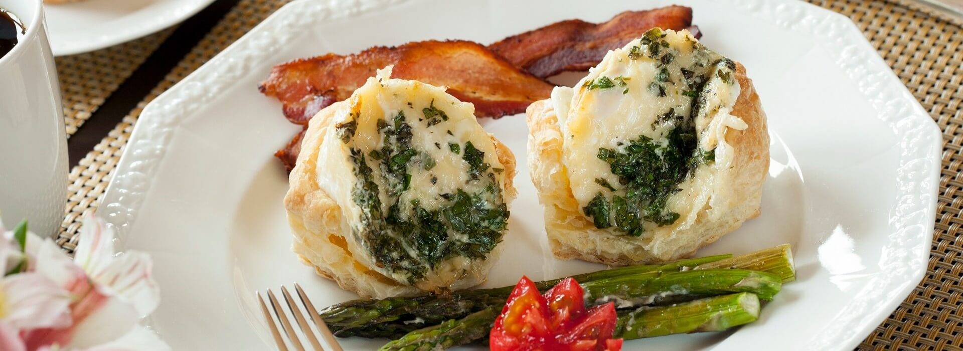 White plate with two egg biscuits, bacon and asparagus