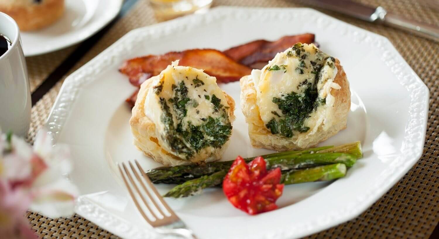 White plate with two egg biscuits, bacon and asparagus